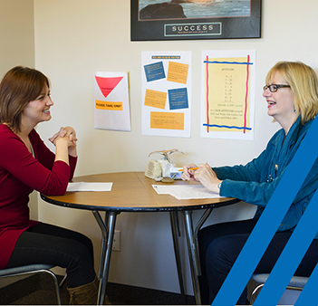 two women sitting at a table having a conversation