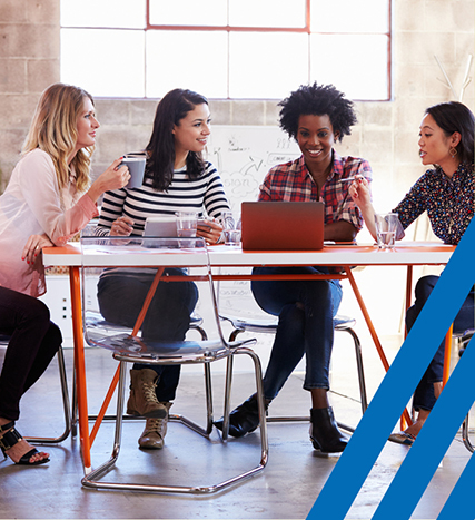 four diverse women sitting at a table together 