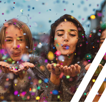 Two women blowing sparkles into the air