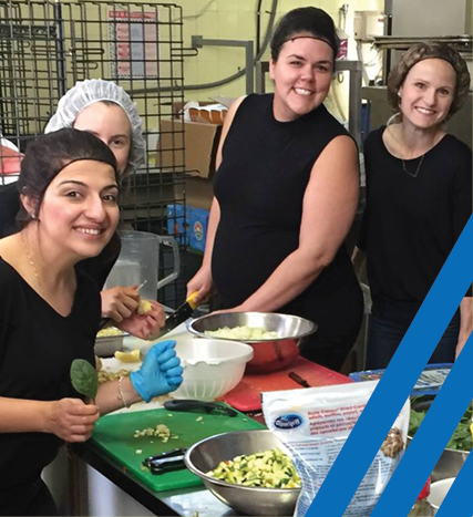 volunteers smiling together in a kitchen preparing a meal