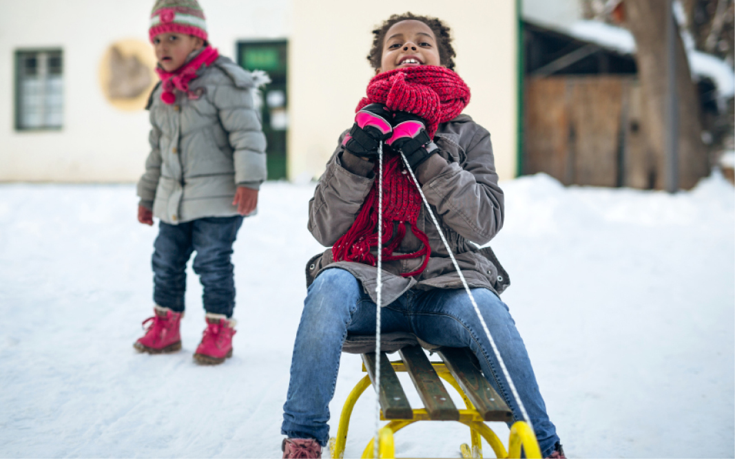 two small children in the snow, child in foreground on sled