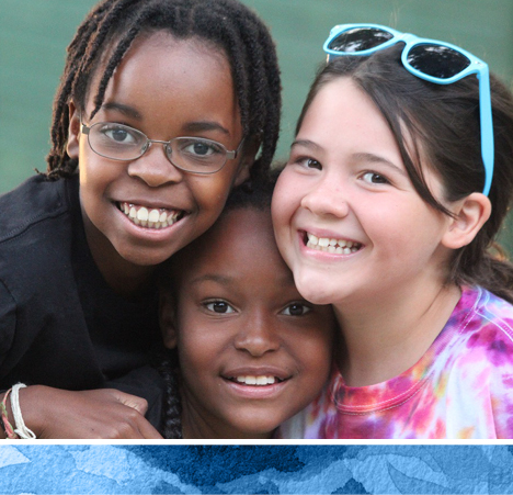 three campers smiling and hugging