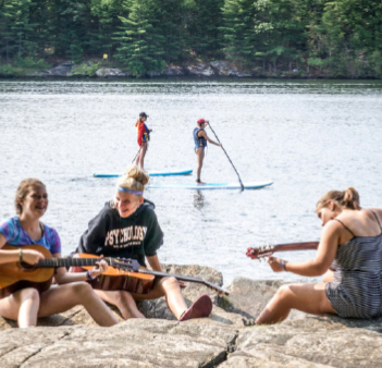 three girls playing guitars at camp