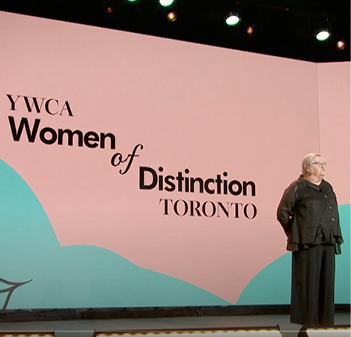 figure standing, Women of Distinction logo on backdrop