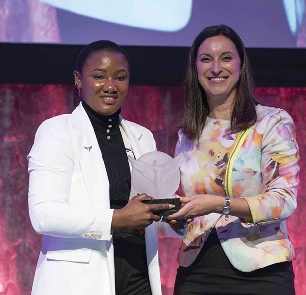 two women smiling and holding an award